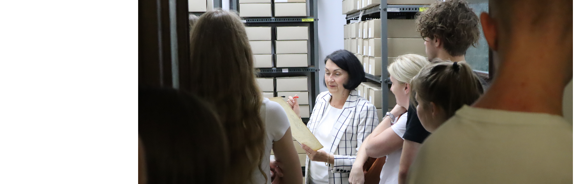 Kierownik Barbara Sypko pokazuje uczniom materiały archiwalne